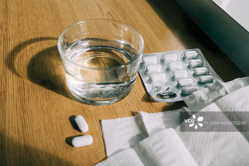 阳光照耀下的药丸、纸巾和一杯水图片素材
