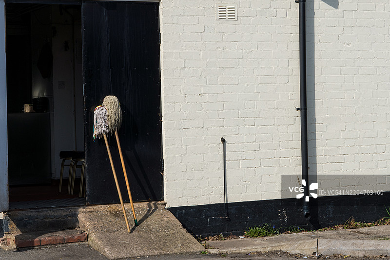两个拖把在酒吧门外晾干。图片素材