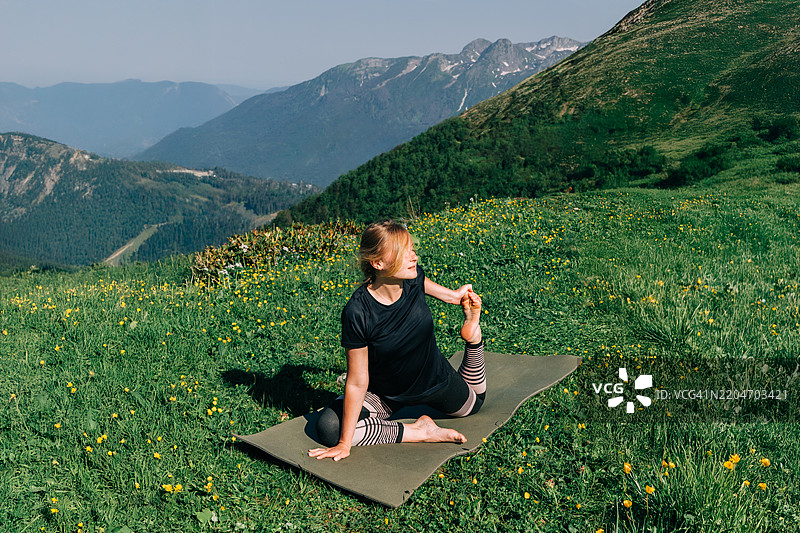 年轻女性在山间草地上做瑜伽图片素材