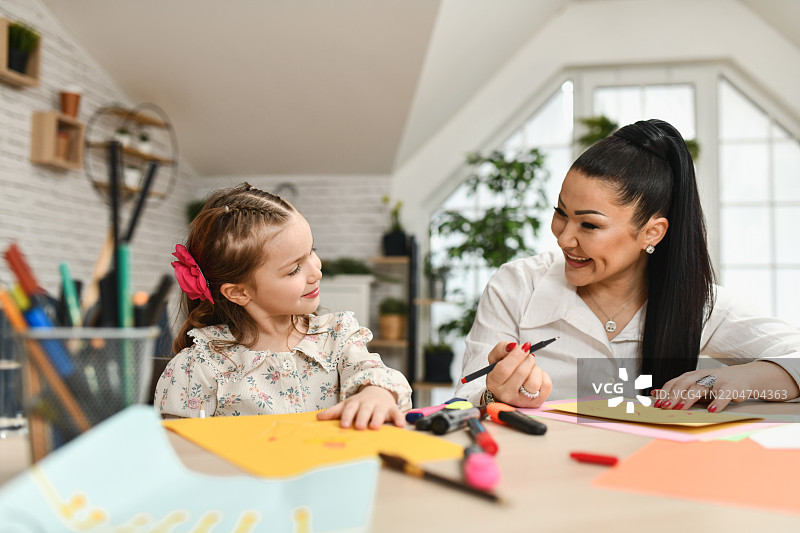 母女在明亮的纸张上享受有趣的绘画时光。图片素材