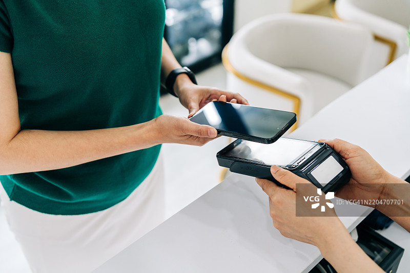 女性在药店柜台使用NFC移动支付图片素材