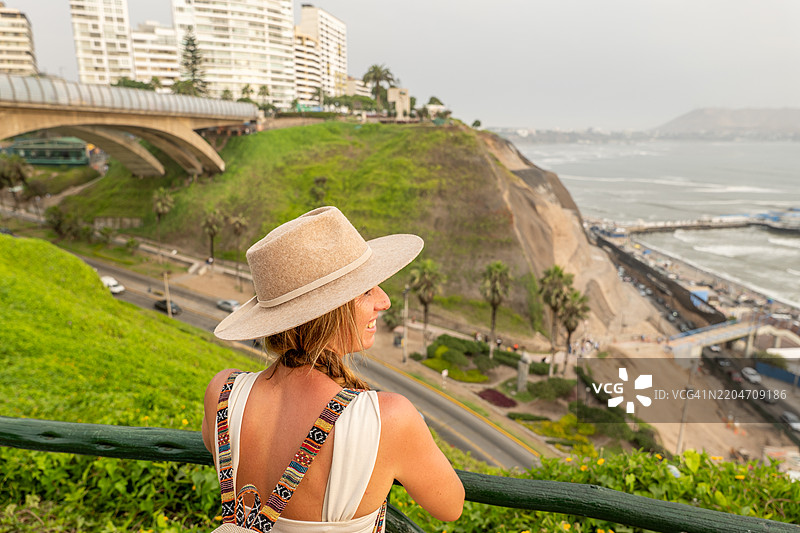 戴着太阳帽的女性在观景台欣赏海滨城市的美景图片素材