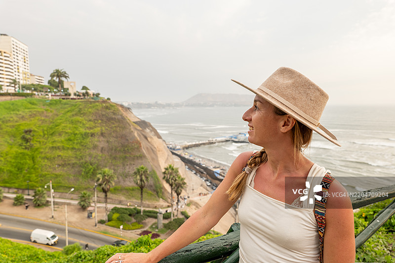 戴着太阳帽的女性在观景台欣赏海滨城市的美景图片素材