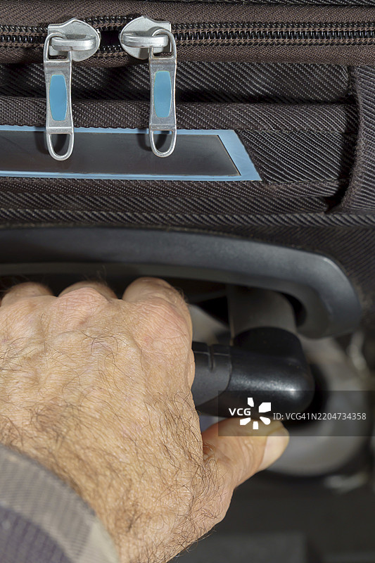 男人的手推着一个黑色行李箱的特写镜头图片素材