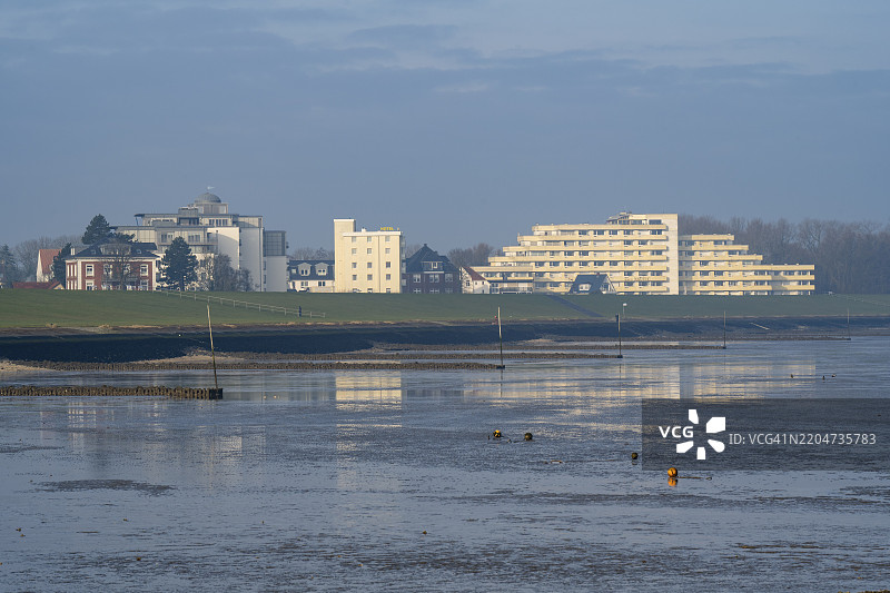 位于德国下萨克森州库克斯哈芬的格里默斯霍恩湾堤坝后面的公寓楼和酒店图片素材
