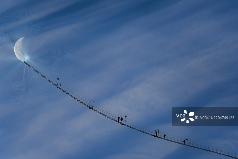 人们走向弦月的剪影悬索桥与天空图片素材