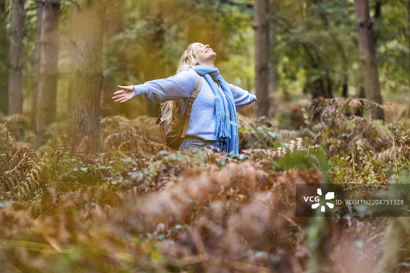 快乐的女人在坎诺克追逐森林的植物中张开双臂。图片素材