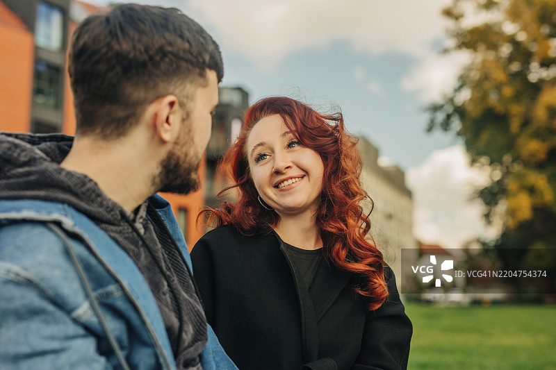 微笑的女朋友在公园里看着男朋友图片素材