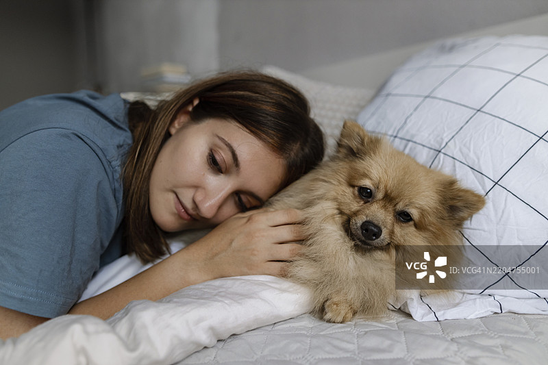 女人躺在床上与狗在一起图片素材