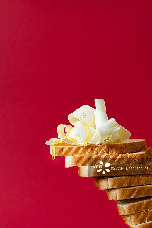 红色背景上的黄油和蜂蜜涂抹的吐司片。概念照片，创意。法式吐司图片素材