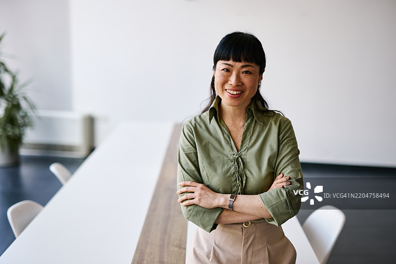 自信的日本女商人在现代办公室微笑并交叉双臂图片素材