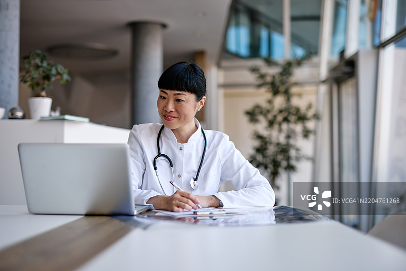 在现代医院中工作的日本医生使用笔记本电脑图片素材