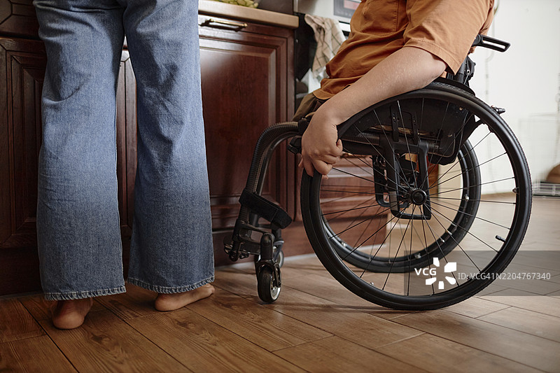 一位坐在轮椅上的男孩在家中帮助母亲准备早餐的特写镜头图片素材