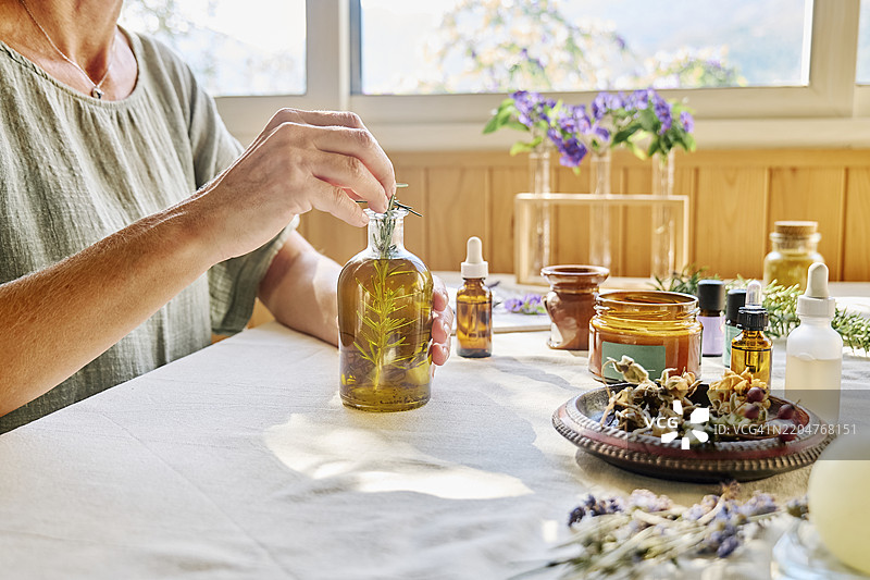 女人在桌子上准备迷迭香油进行治疗图片素材