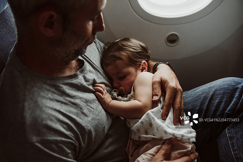 父亲与婴儿女儿在飞机上睡觉图片素材