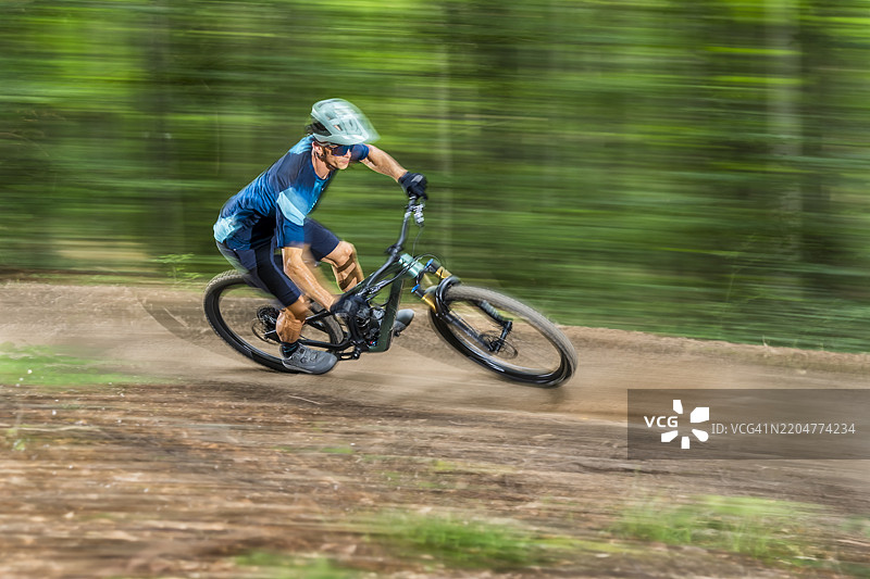 运动员在森林中的泥土路上骑山地自行车图片素材