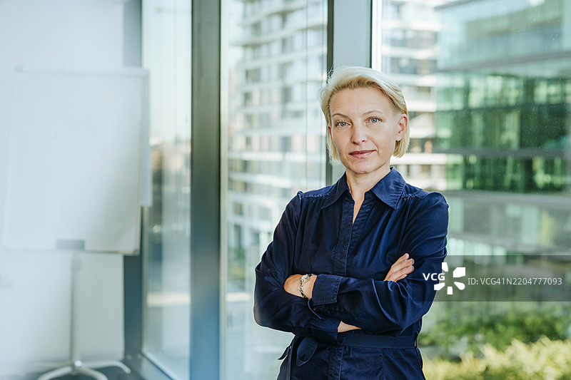 自信的女商人在办公室里双臂交叉站立图片素材