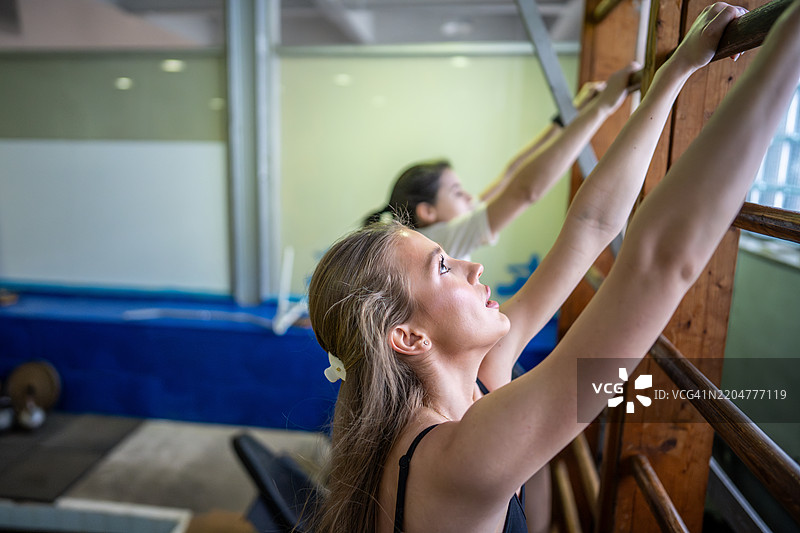 专注的女运动员在体操双杠上训练，通过静态练习增强手臂力量图片素材