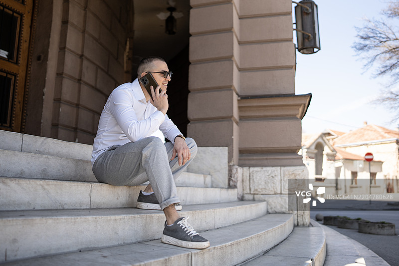 男人坐在城市环境中的楼梯上使用手机图片素材