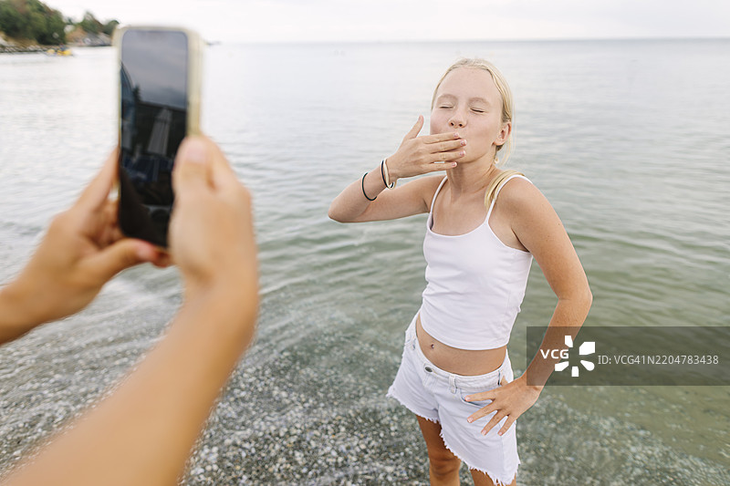 母亲在海滩上用智能手机给女儿拍照图片素材