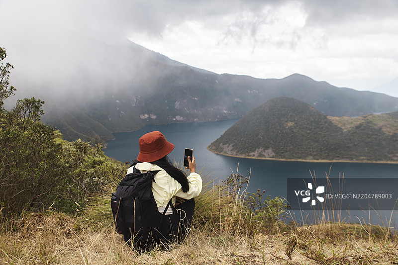 背包客坐在库伊科查湖附近用智能手机拍照图片素材