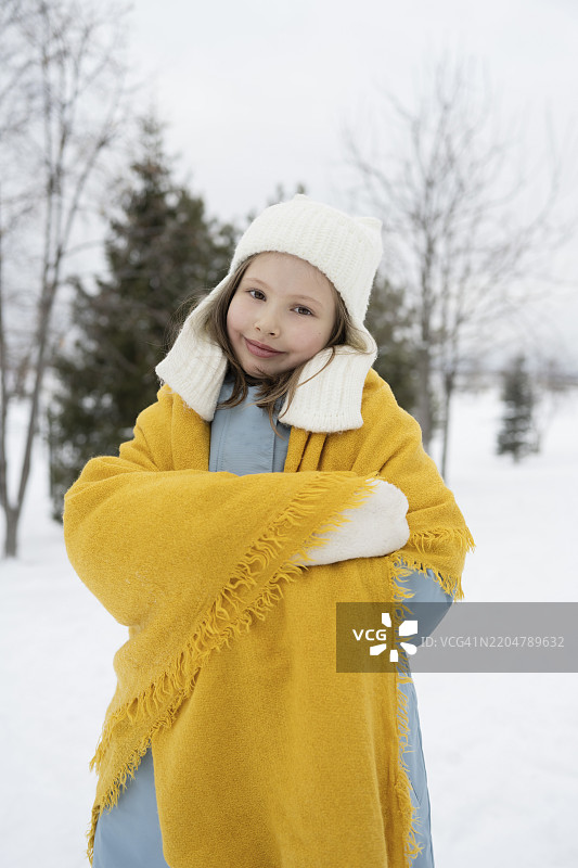 可爱的女孩裹着披肩站在冬季森林中图片素材