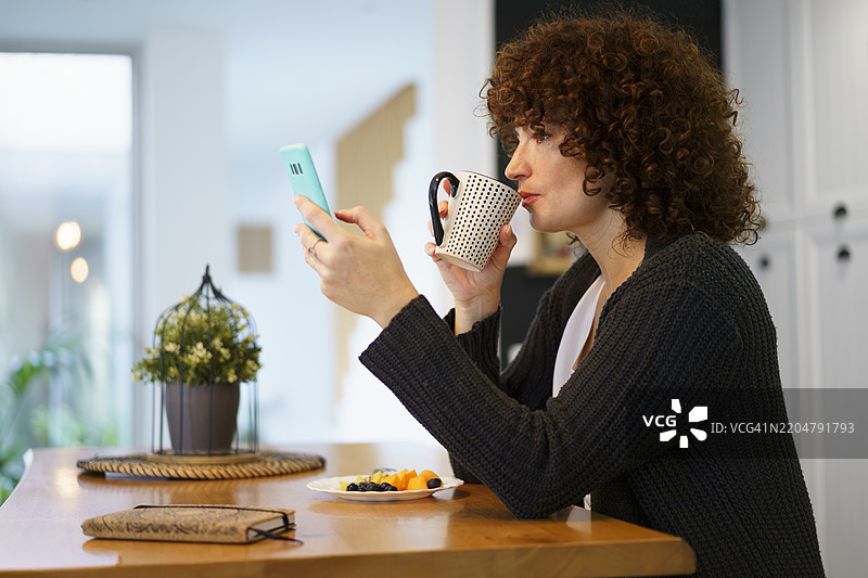 女人在家喝咖啡并使用智能手机图片素材