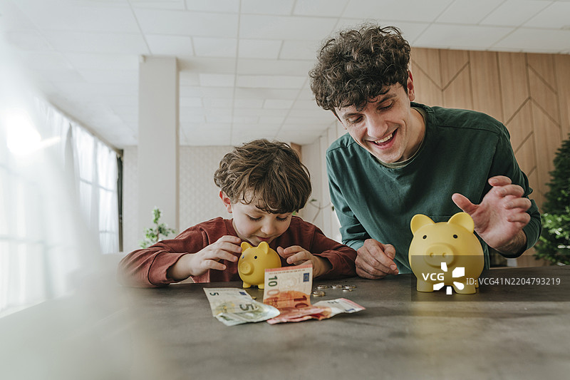 父亲和儿子在家里收集存钱罐里的钱图片素材
