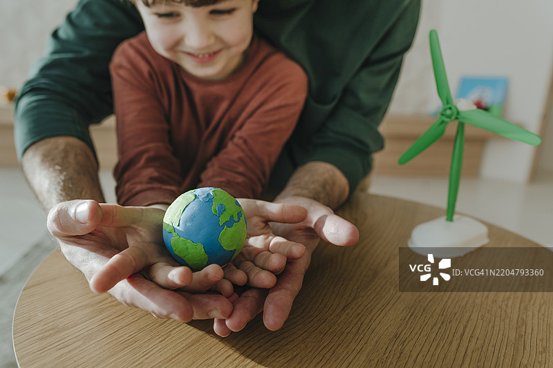 男孩在家中与父亲一起手握地球仪图片素材