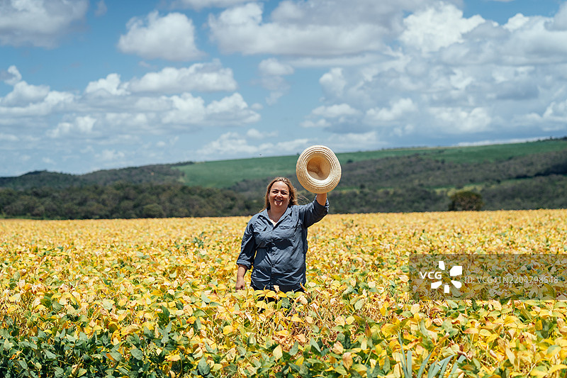 女农民在种植园中挥动帽子图片素材