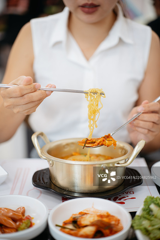 亚洲女性在餐厅里手持一块泡菜，享用韩国泡菜拉面图片素材