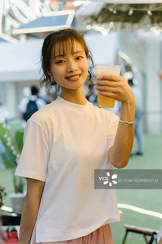 一位女性在啤酒龙头前举着一杯啤酒图片素材