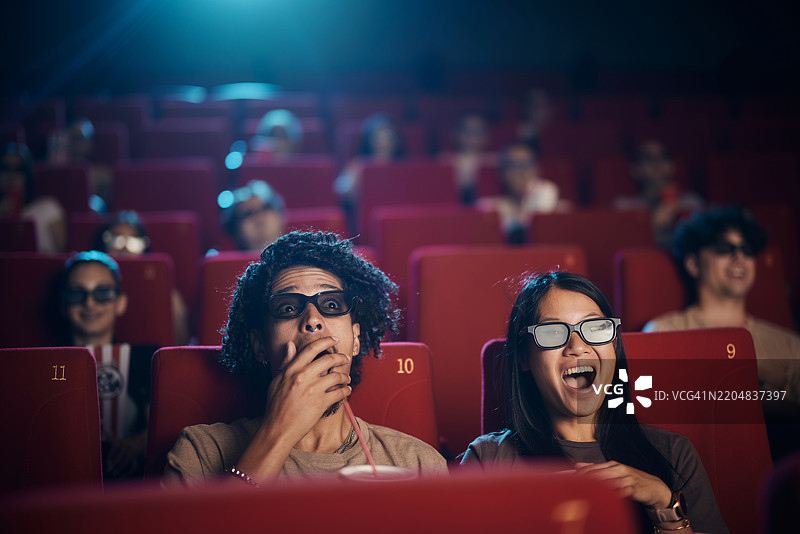 惊讶的情侣在电影院享受3D电影。图片素材
