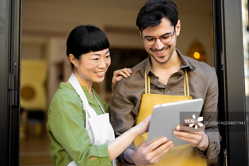 一对餐厅服务员在等待客人时使用平板电脑图片素材