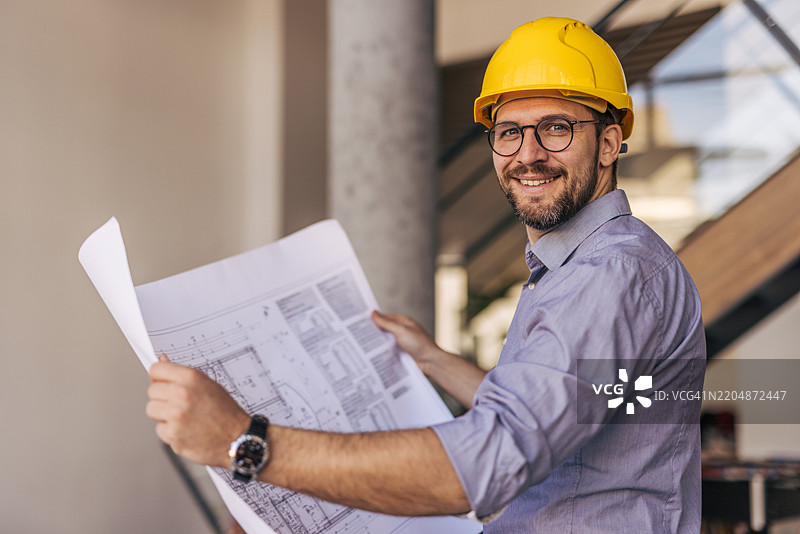 建筑师微笑着在施工现场手持蓝图图片素材