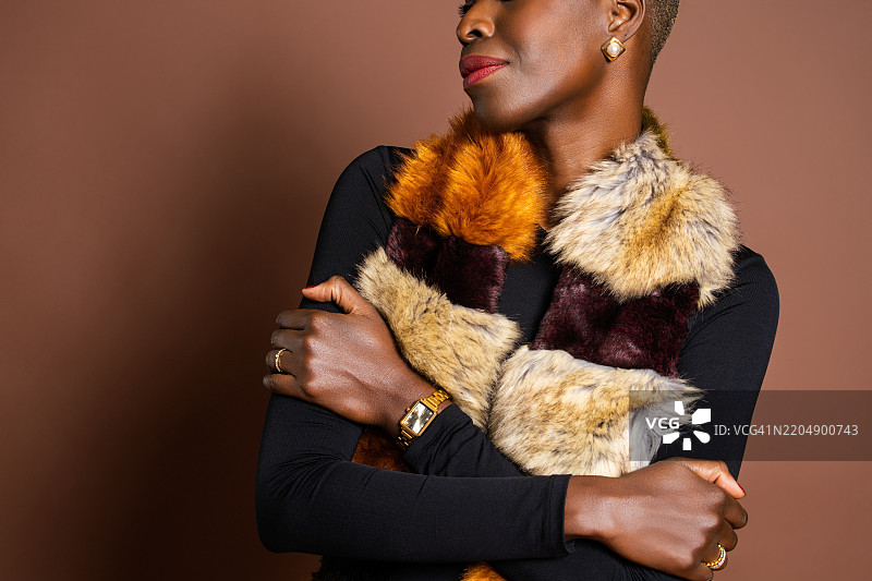 时尚的黑人女性佩戴着人造毛皮披肩和金色手表图片素材