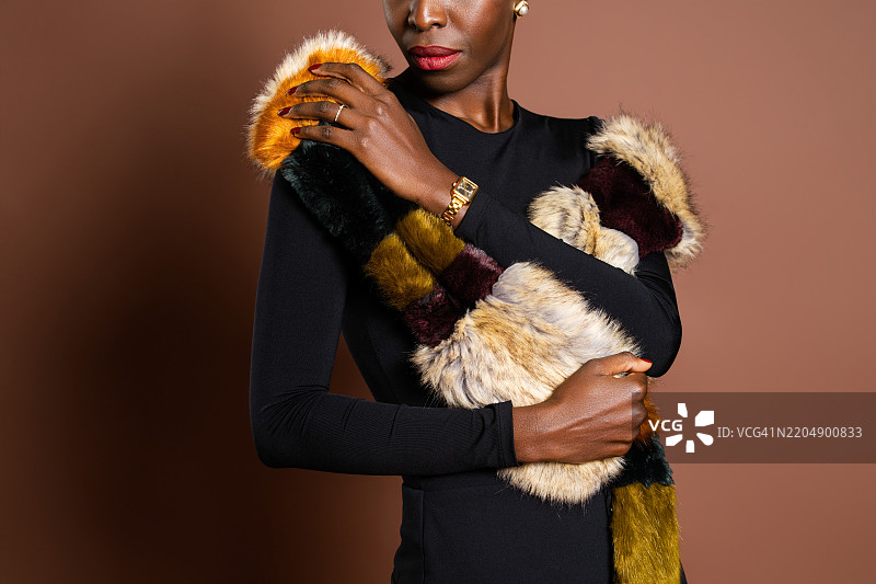 时尚模特佩戴着五彩斑斓的仿毛皮围巾和金色手表图片素材