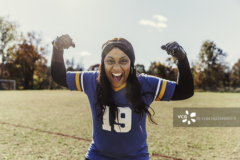 快乐的女性足球运动员在球场上展示肌肉图片素材