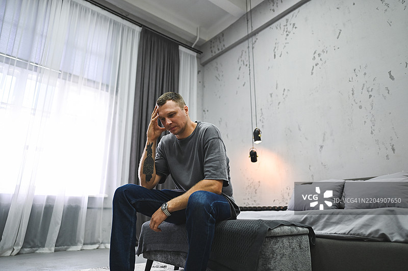 穿着奢华西装的男人坐在床上。图片素材