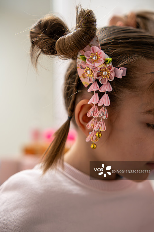 年轻女孩佩戴着带有粉色花朵和铃铛的传统日本发饰图片素材