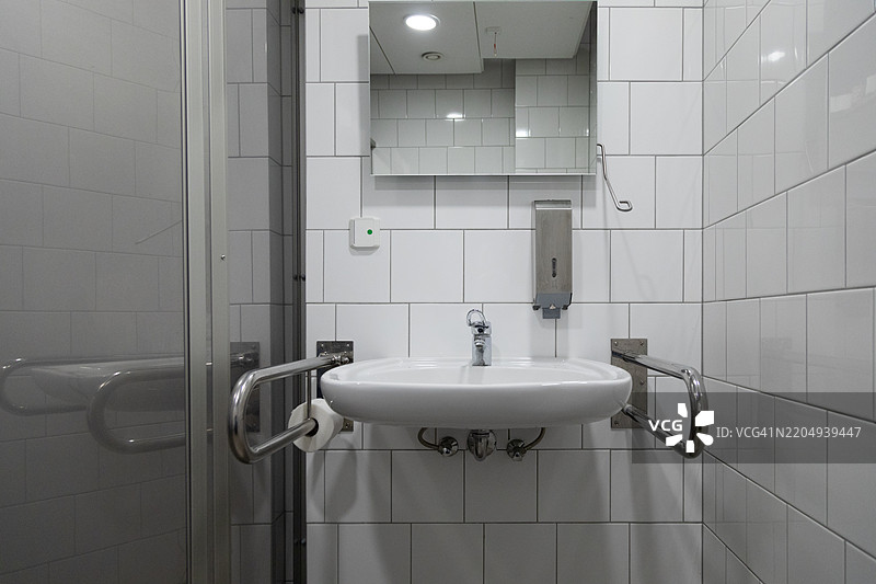 无障碍浴室，配有安全扶手和现代白色瓷砖设计图片素材