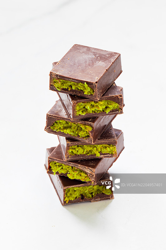 素食甜点。迪拜巧克力。巧克力内填充酥脆的卡塔伊菲面团和翡翠般的开心果酱。特写。白色背景。图片素材