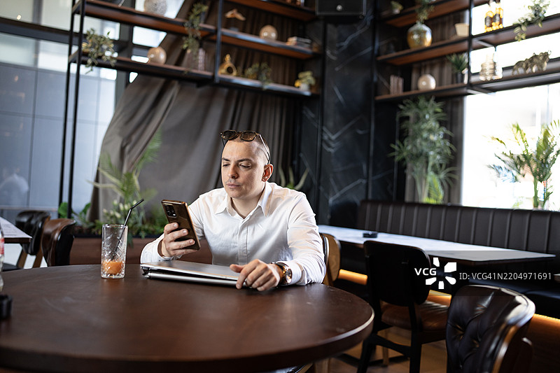 商人在现代咖啡馆中使用智能手机，享受轻松的氛围图片素材