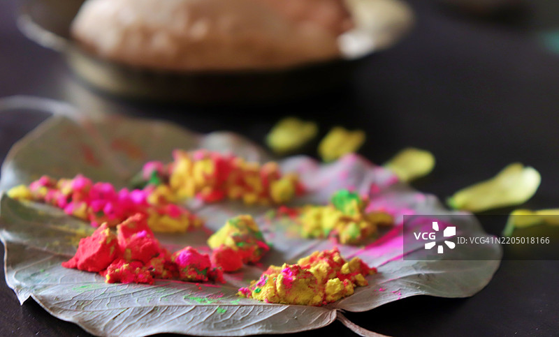 五彩缤纷的粉末洒在菩提树叶上，铜盘中的甜饺子，印度的霍利节庆祝色彩的节日图片素材
