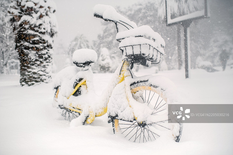 热带气候中异常寒冷天气下城市街道上的自行车在降雪。全球气候变化和生态问题的概念。图片素材