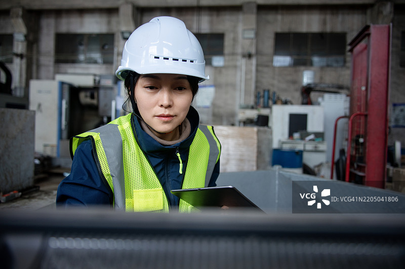 亚洲女性工程师在金属加工厂使用数字平板电脑工作图片素材