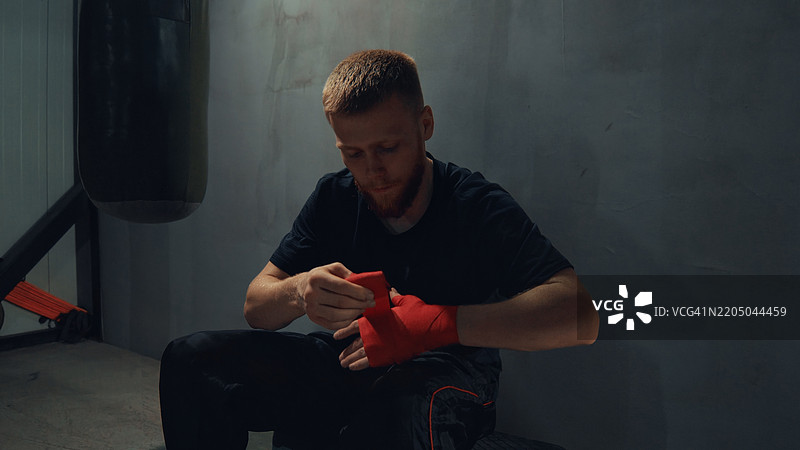 拳击手用红色拳击绷带包裹双手，准备训练图片素材
