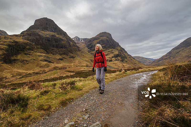 在苏格兰格伦科的三姐妹山下徒步旅行的女性。图片素材
