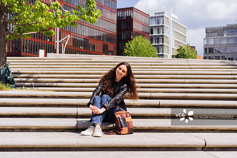 年轻女性在现代城市环境中的楼梯上放松图片素材
