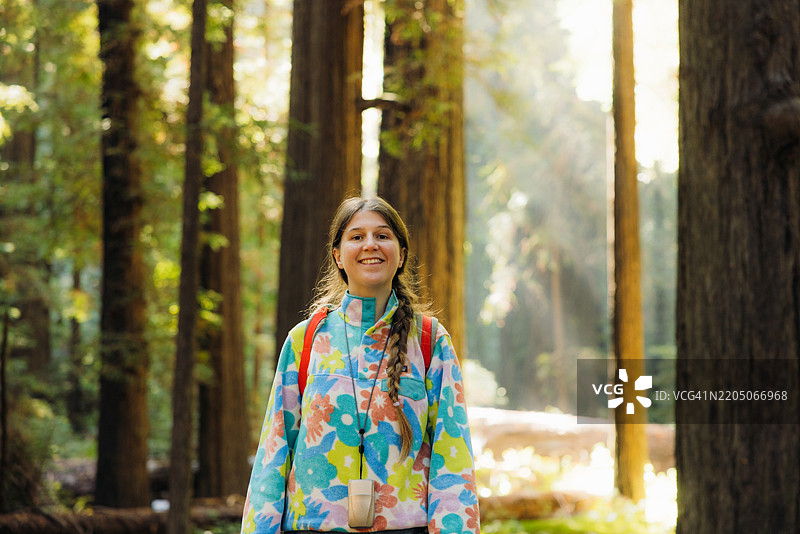 宁静的女性背着背包在红木树间晨跑图片素材